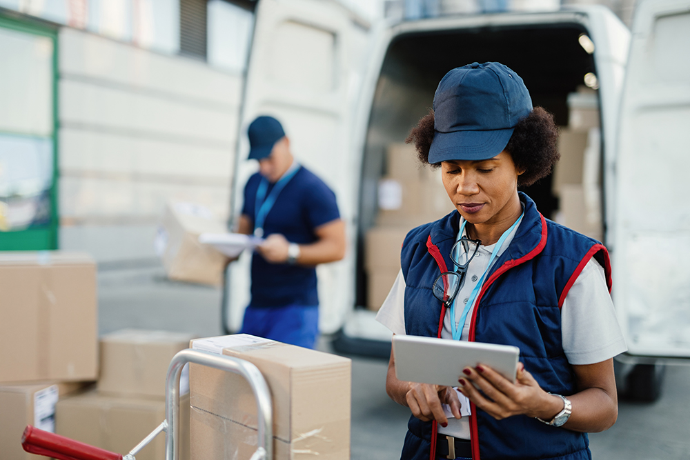 black female deliverer using digital tablet while preparing pack